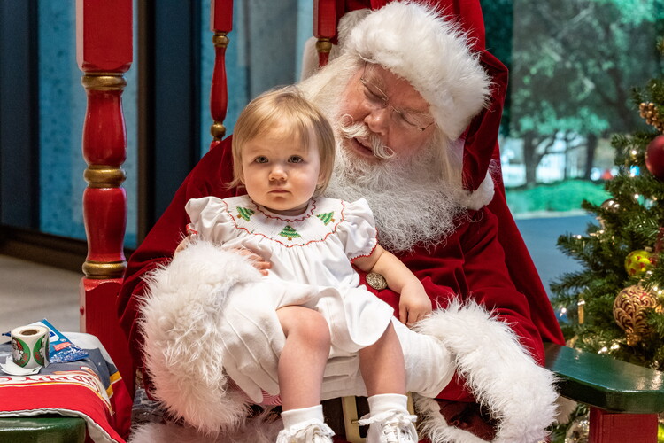 Santa Claus holds a toddler on his lap.
