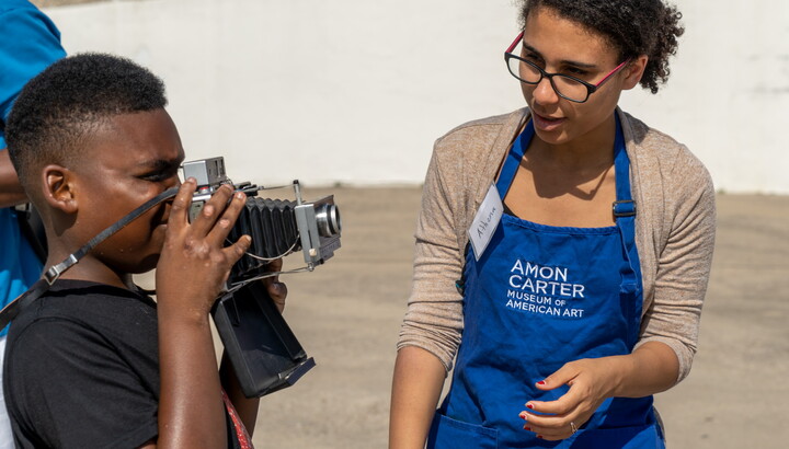 Boy with a camera helped by woman