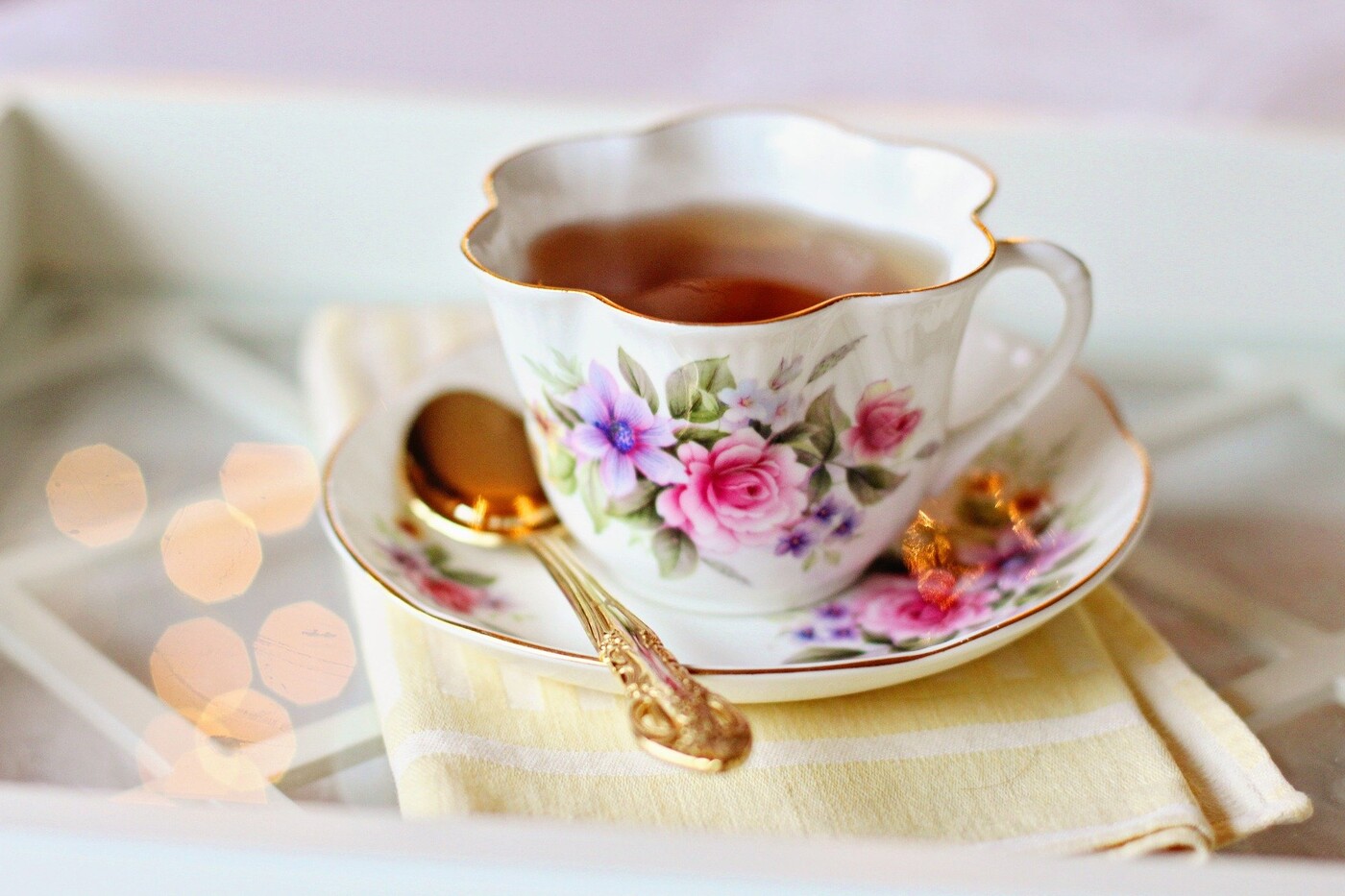 Tea cup and saucer with a gold spoon resting on the saucer.