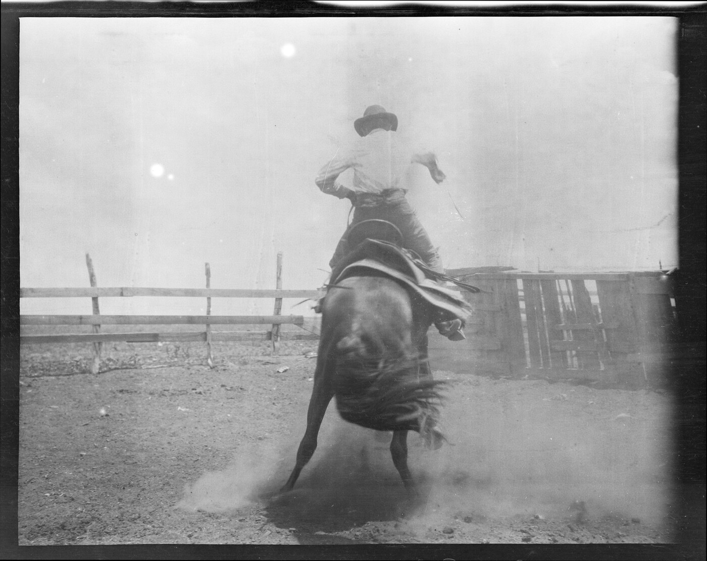 Riding a bronc in a corral somewhere in the cattle country. Texas or
