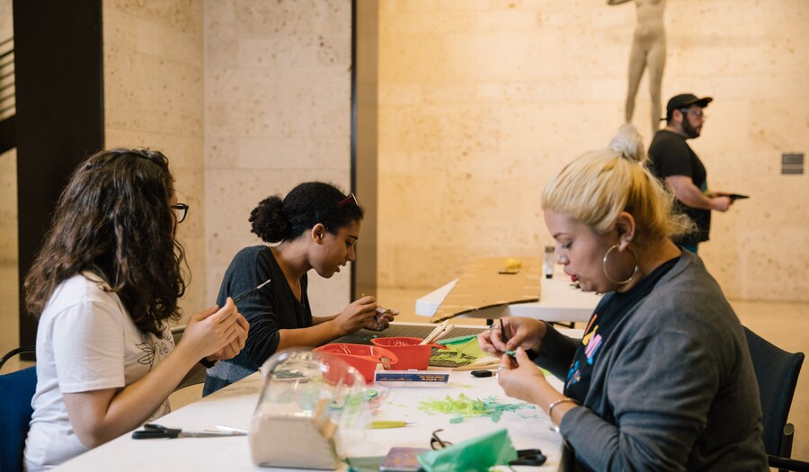 A group of Museum visitors seated at a table making art.