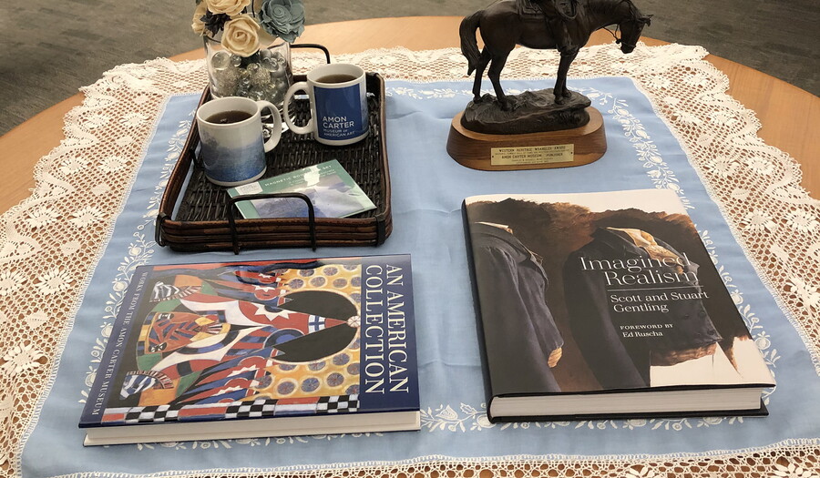 A table with two Museum catalogues, a sculpture, and a tray with tea cups.