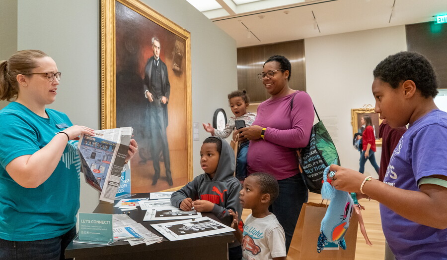 A Carter staff member interacts with a family in front of a painting.