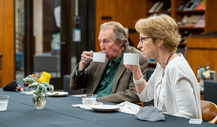 Two people sit at a table and sip on tea.