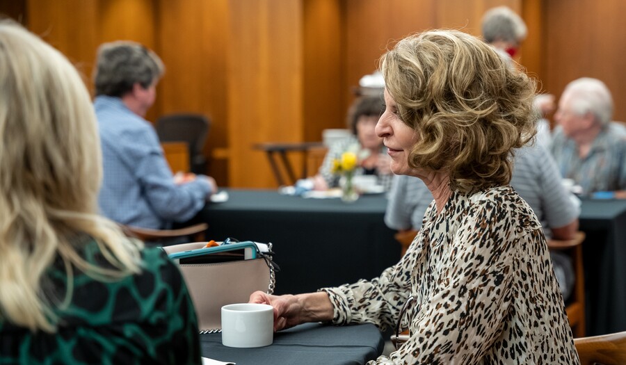 Adults drink tea at tables in the Carter's Library.
