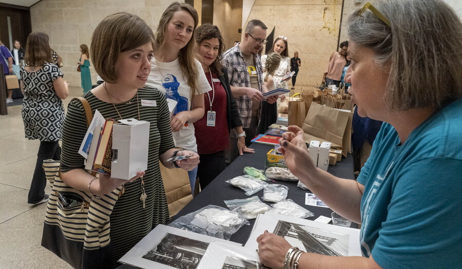 A group of adults line up in front of a table where a Carter educator is presenting them with materials.